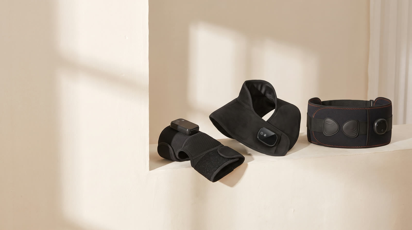 The Unknot Heat Belt, Neck and Shoulder Wrap and Knee Wrap resting on a sunlit plaster ledge